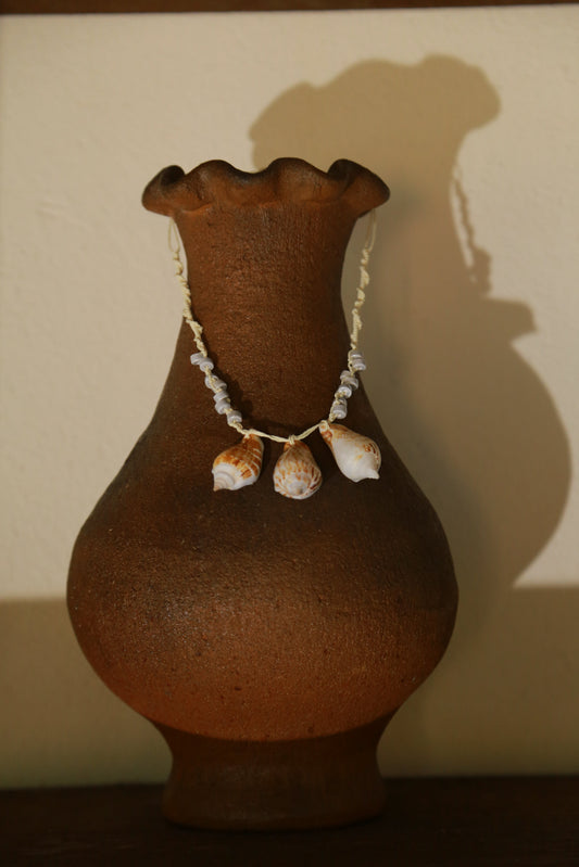 Trois Tessellées Vân Cam necklace on terracotta vase, full view